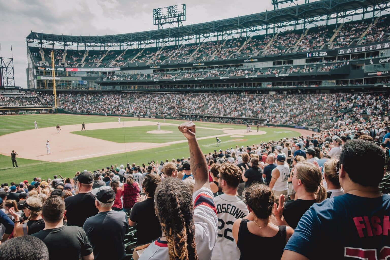 Large crowd cheering as they watch a baseball game.