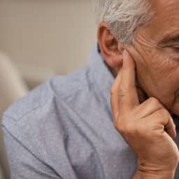 Man holding his ear looking sad or stressed.
