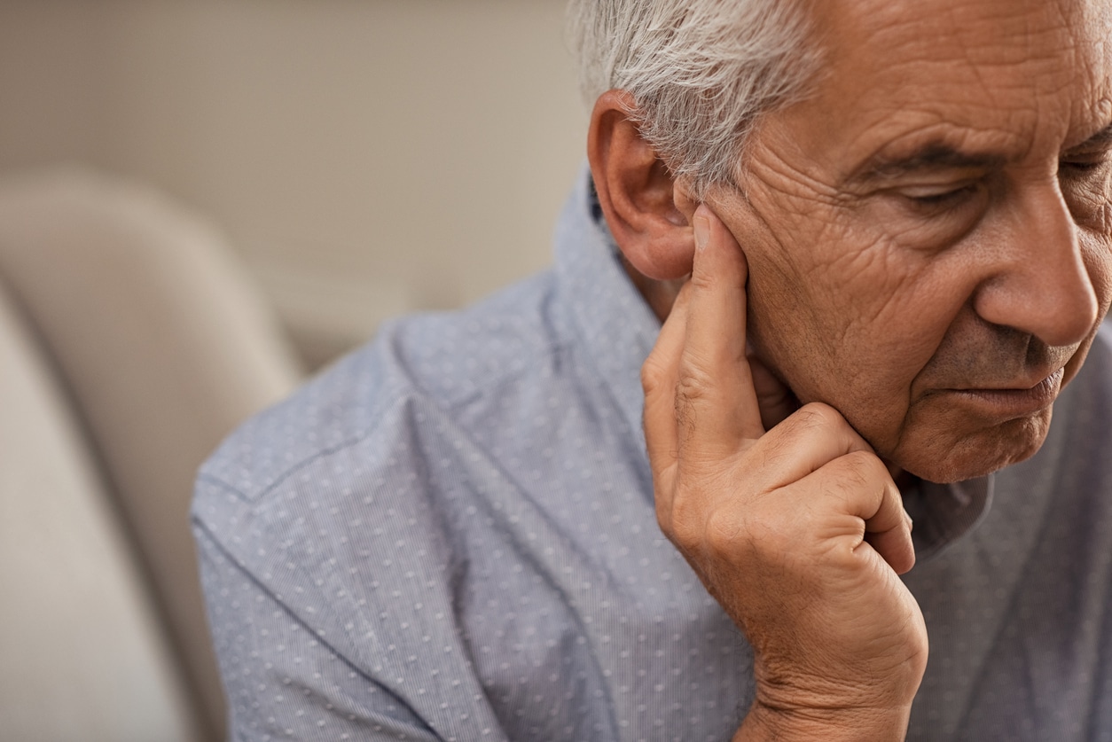 Man holding his ear looking sad or stressed.