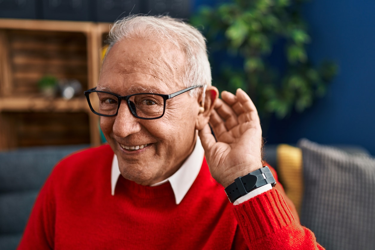 Happy man showing off his hearing aid.