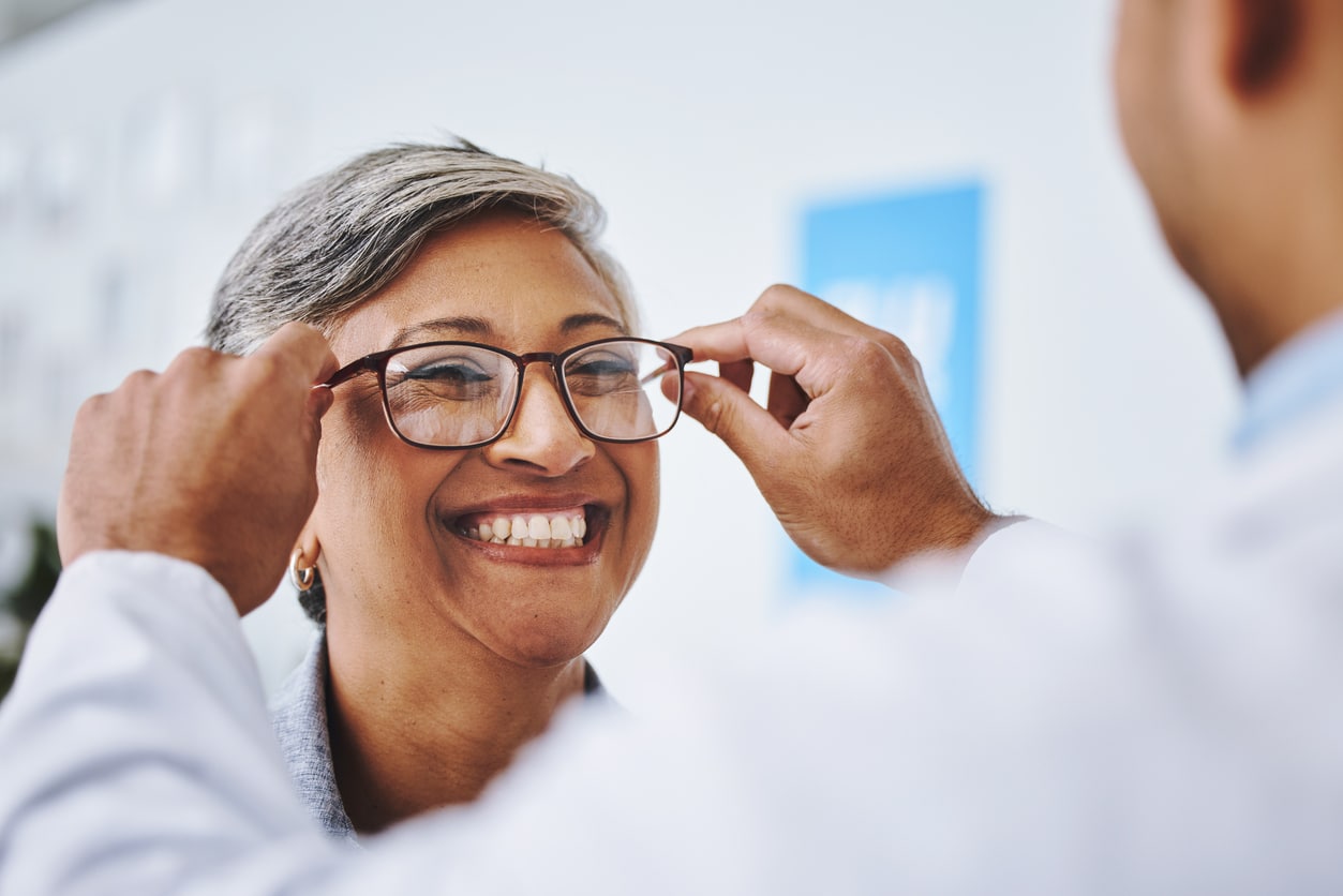 Woman trying on new glasses at the eye doctor.