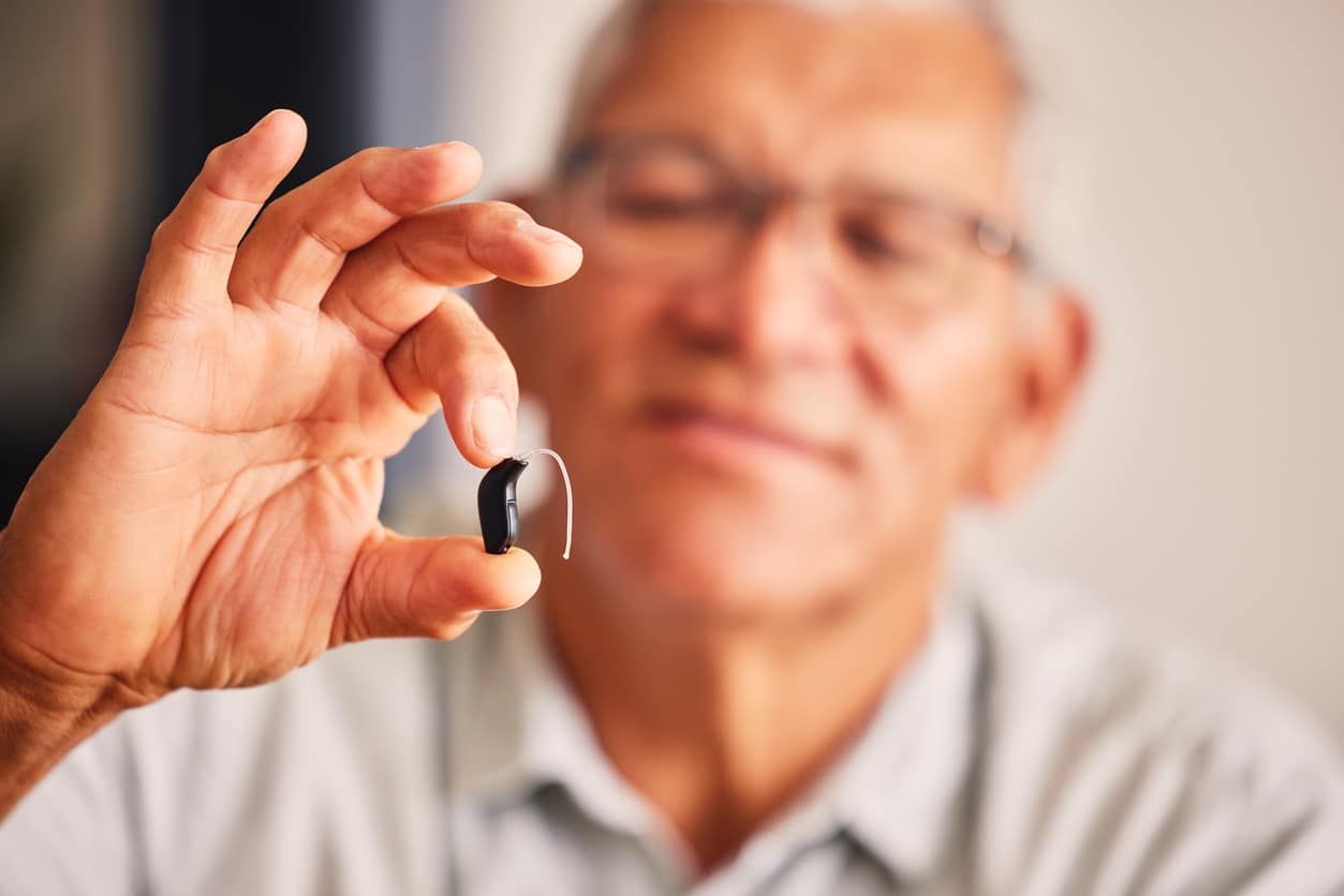 Man holding up his new hearing aid.