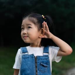 Young girl holds hands together outside